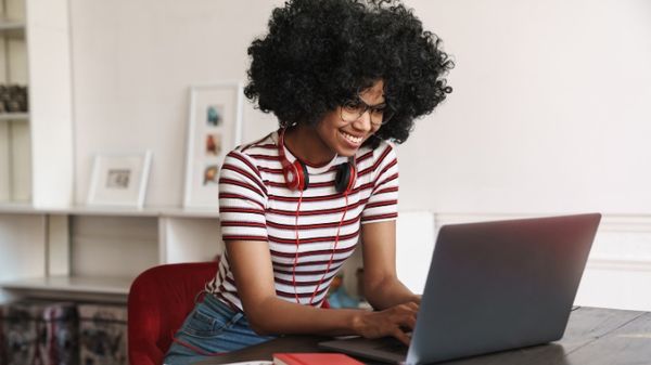 Image: smiling woman with headphones looking at a laptop; Article: Popular articles for musicians