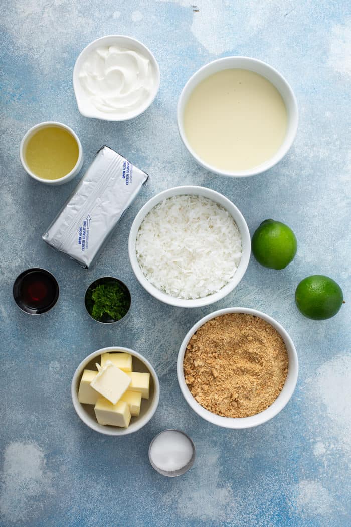 Ingredients for key lime cheesecakes on a blue countertop