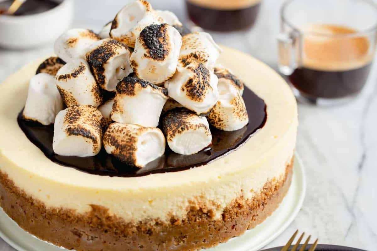 Toasted marshmallows piled on top of a cheesecake on a serving platter