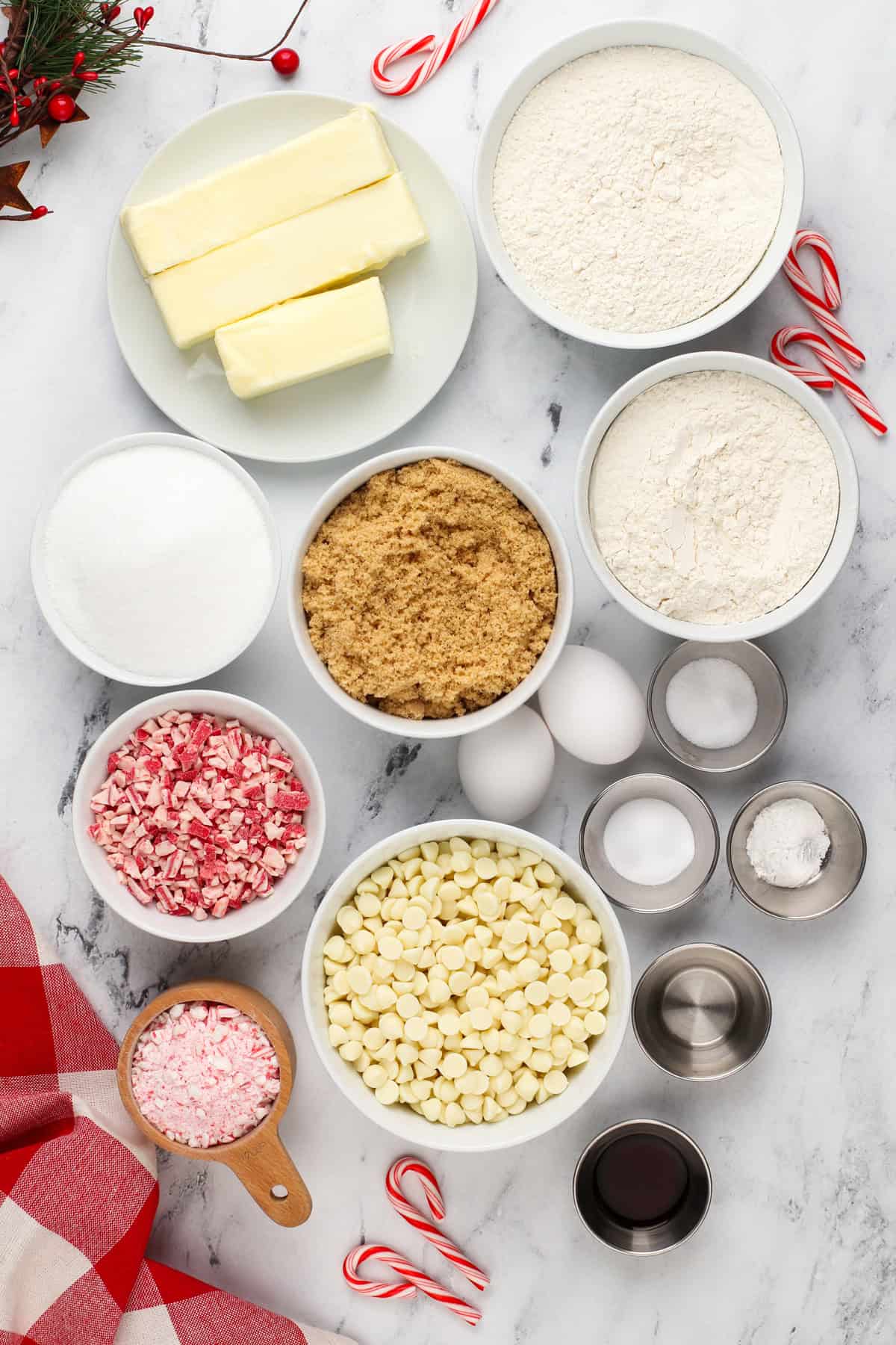 Ingredients for white chocolate peppermint cookies arranged on a marble countertop.