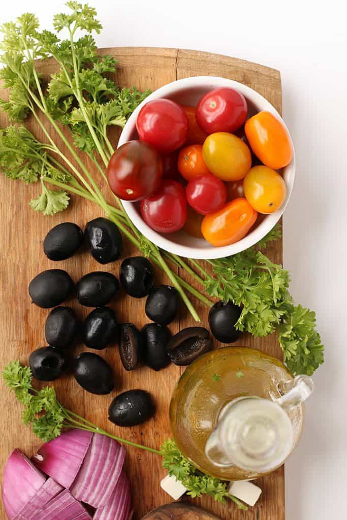 Cherry tomatoes, olives, and parsley on cutting board