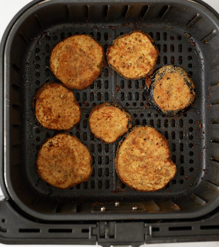 The cooked eggplant slices in the air fryer basket.