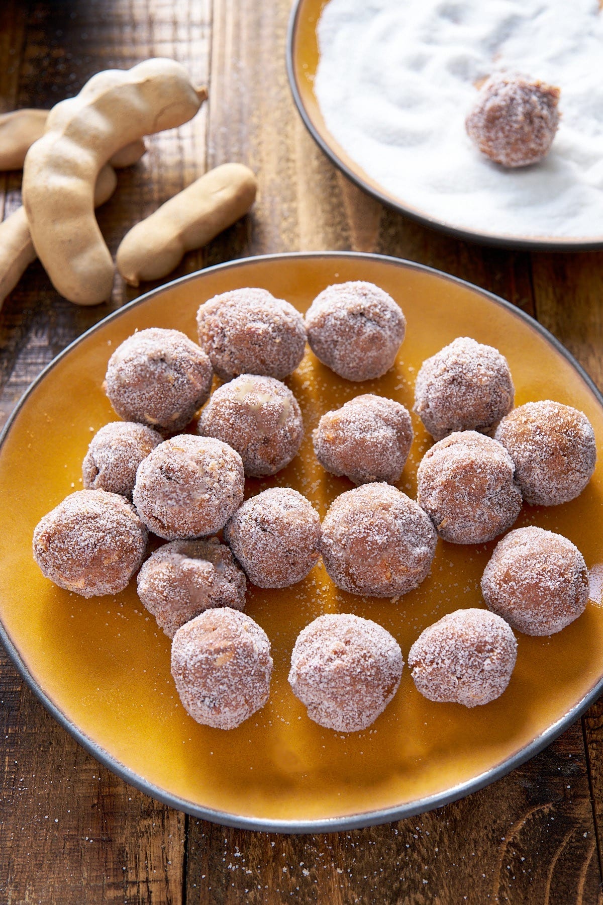 tamarind balls on plate with whole tamarind balls in background