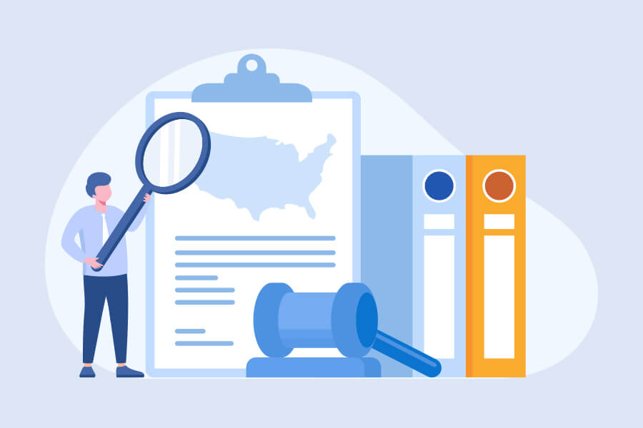 A person holding a magnifying glass examines a document with a map of the U.S., next to a gavel and two binders