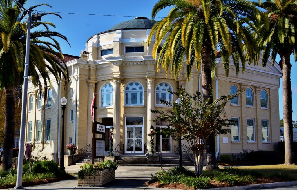 Beautiful, angled church building with palms on a corner.