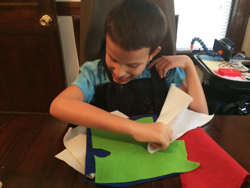 Blind boy making the dragon wings from felt