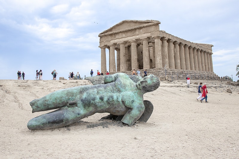 a large scultpure in front of a temple seen  while seeing Sicily by car