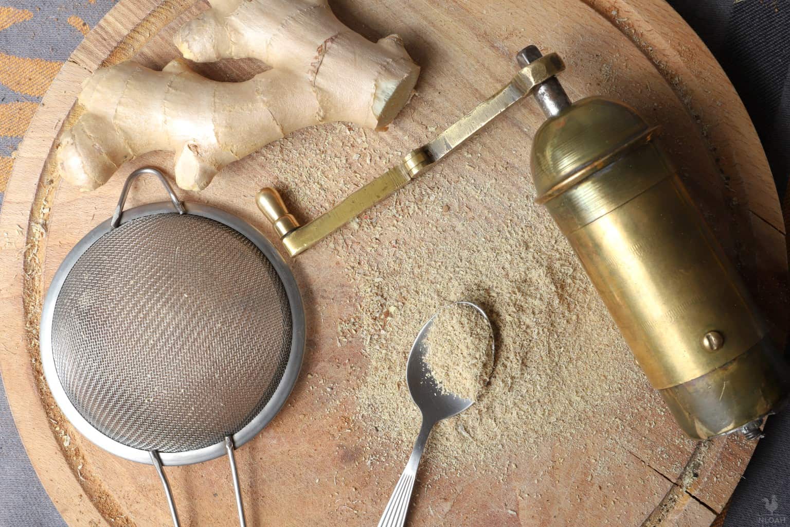 powder ginger next to ginger root grinder and strainer