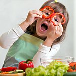 A young girl having fun in the kitchen while preparing vegetables