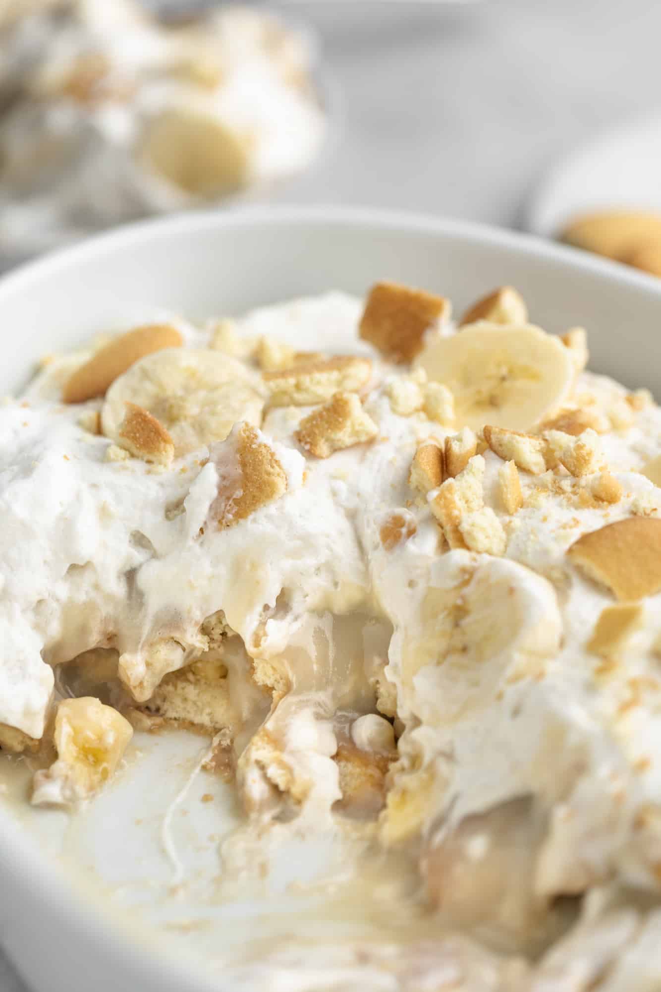 vegan banana pudding in a large glass dish with a scoop missing.