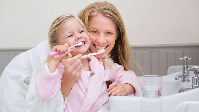 Mother and daughter brushing their teeth and Greeley dentist