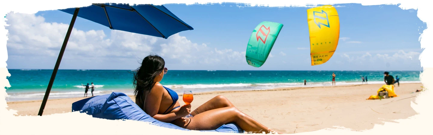 a woman tanning under the sun watching kite-surfers