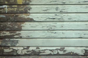 peeling paint due to moisture on wood siding on an old house