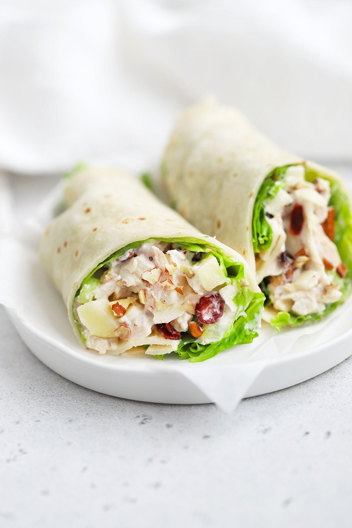 Close-up view of an Apple Cranberry Chicken Salad Wrap made with a gluten-free tortilla and lettuce. 