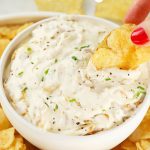 dipping kettle chips into a bowl of greek yogurt french onion dip