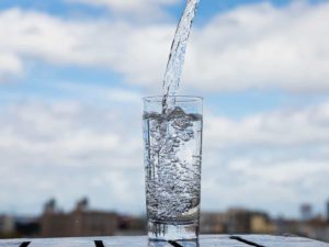 water poured into a clear glass with blue sky in the background