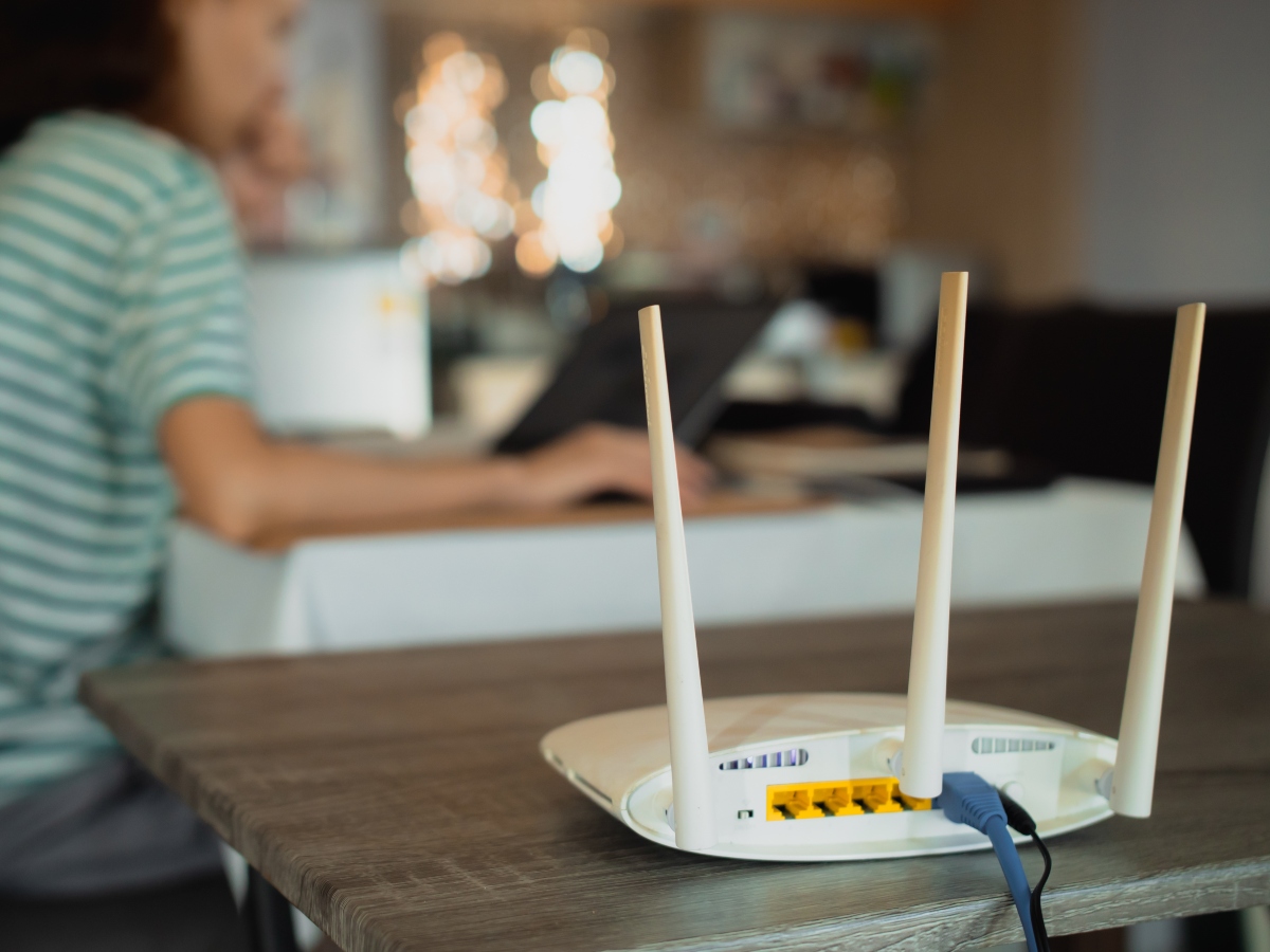 A woman is working at home using a modem router, connecting the Internet to her laptop.