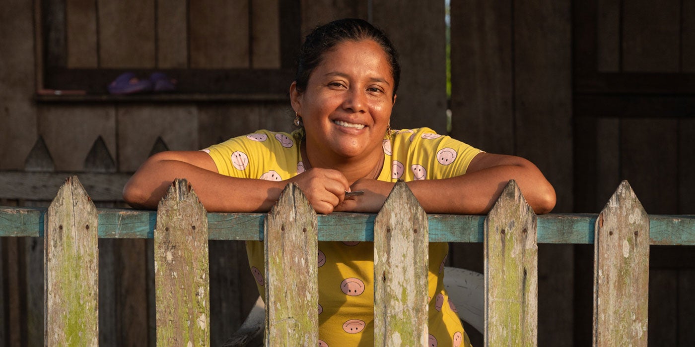 Mujer latinoamericana sonriente posa sobre una cerca.