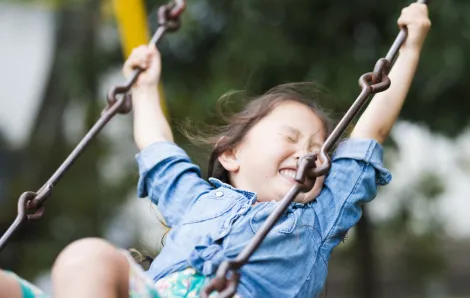 happy girl swinging on swing playing at playgrounds reopening for south sound families