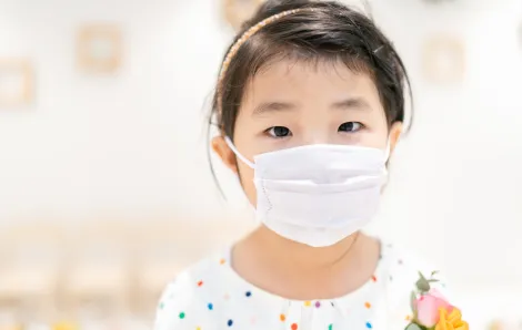 little girl looking at the camera wearing a mask