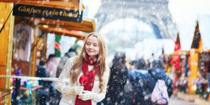 A youg woman dressed for winter and holding a candied apple at a Christmas Market near the Eiffel Tower in Paris