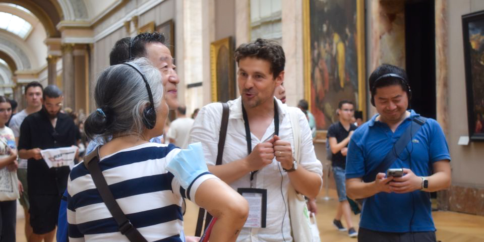 Travelers on a private guided tour of the Louvre Museum as the guide explains the history and technique of the art works