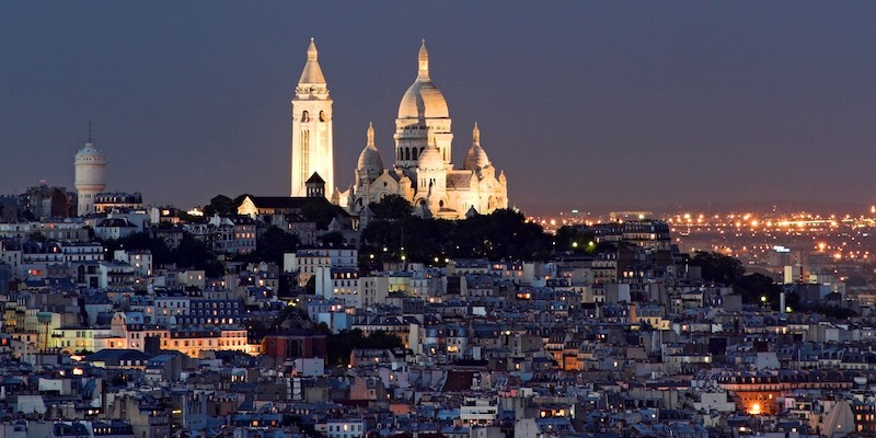 Sacre Coeur Basilica in Paris with its white domes lit up against the night sky