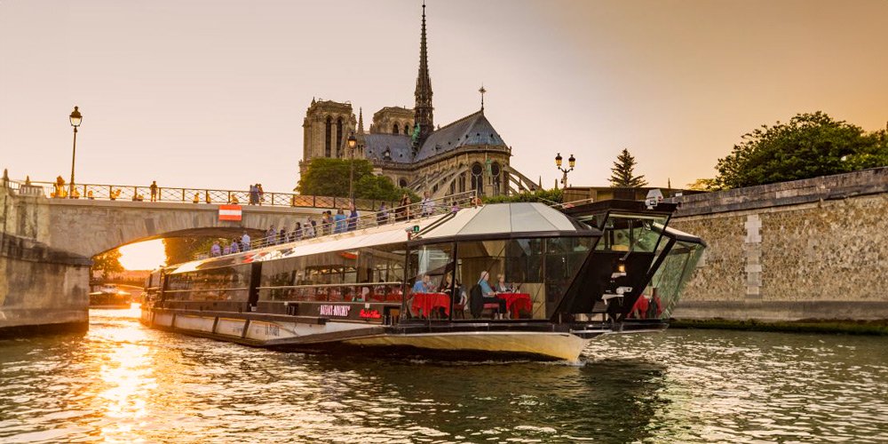 A Bateaux Mouches Dinner Cruise boat sails beneath Notre Dame in Paris