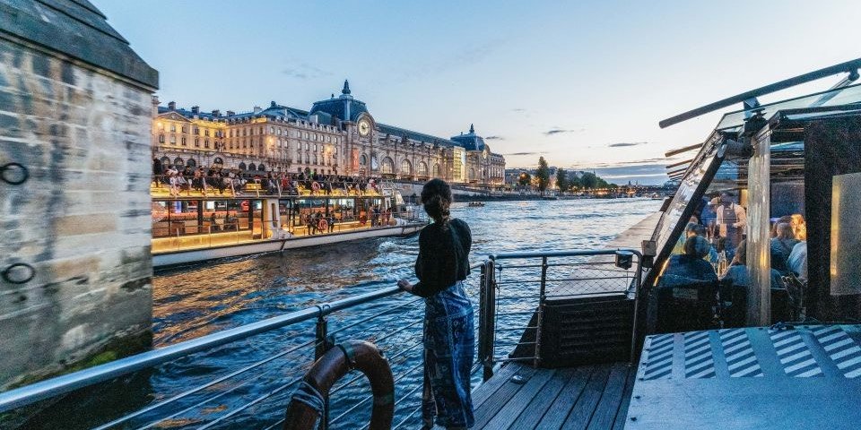 A woman views Paris from a river boat during a Bateaux Parisiens Dinner Cruise