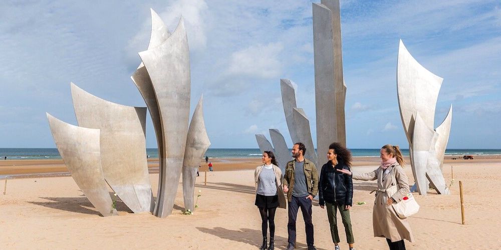 Visitors view the memorial sculpture during a D-Day Tour from Paris