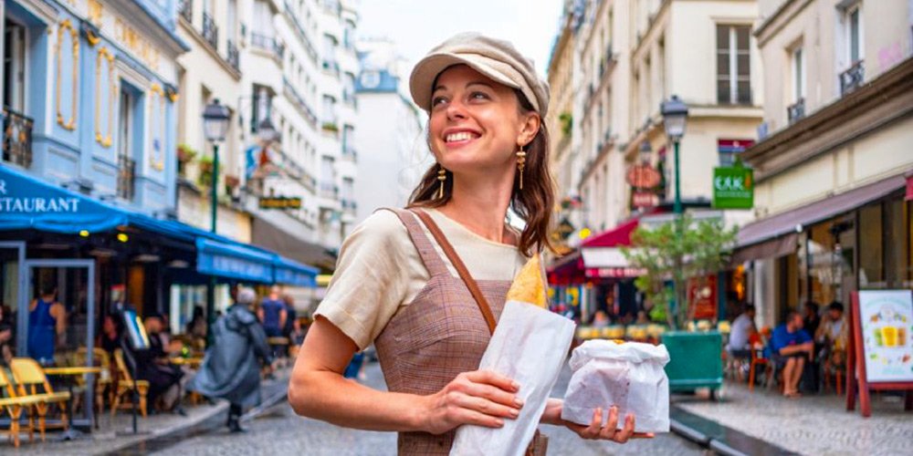 Woman holding a baguette on a Food & Wine tour of the Marais