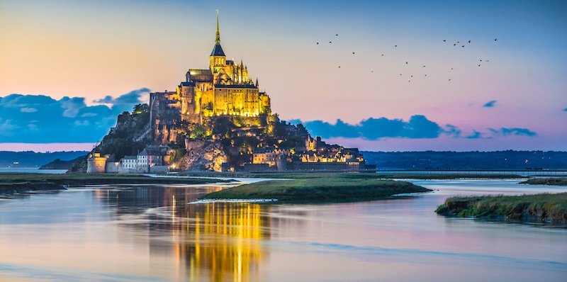 The eerie beatury Mont Saint-Michel lit at night on its disappearing island