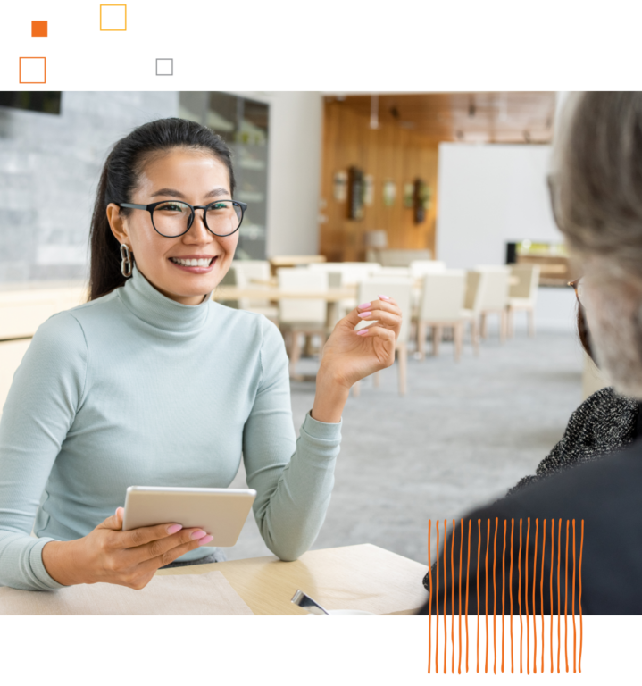 smiling woman looking across table at another person