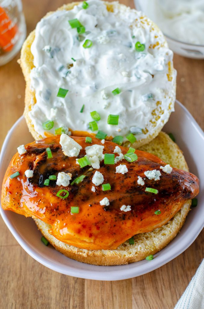 opened face buffalo chicken sandwich topped with bleu cheese crumbles