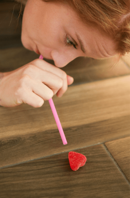 Girl blowing a heart with a straw