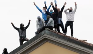 Inmates stage a protest against new rules to cope with coronavirus emergency, including the suspension of relatives' visits, on the roof of the San Vittore prison in Milan, Italy, Monday, March 9. Jails and prisons in the U.S. will likely also be contending with coronavirus cases soon. (AP Photo/Antonio Calanni)