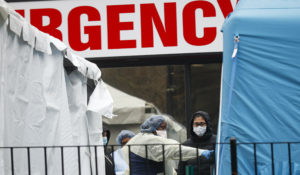 A medical worker directs a patient to enter a COVID-19 testing site at Elmhurst Hospital Center, Wednesday, March 25, 2020, in New York. (AP Photo/John Minchillo)