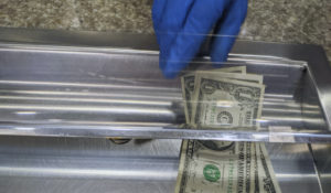 A bank teller wears gloves while handling a transaction because of prevention efforts during the coronavirus outbreak in the Atwater Village neighborhood of Los Angeles Friday, April 3, 2020. Some 40 million Californians are under a state order to stay at home except for essential trips, such as buying food or medicine, and fear of spreading contagion remains high. (AP Photo/Damian Dovarganes)