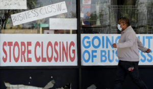 A man looks at signs at a store closed due to COVID-19 in Niles, Illinois. (AP Photo/Nam Y. Huh, File)