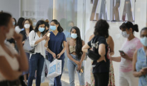 Customers wait in line to enter a store at Garden State Plaza in Paramus, New Jersey. (AP Photo/Seth Wenig)