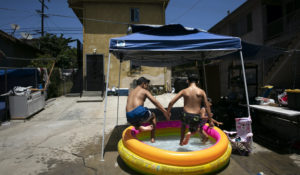 Vincent Velarde, 11, left, and his brother, Emilio, 12, jump into an inflatable pool in Los Angeles, Friday, July 17. (AP Photo/Jae C. Hong)