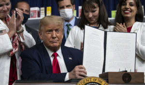 President Donald Trump holds up a signed executive order on lowering drug prices, in the South Court Auditorium in the White House complex, Friday, July 24, 2020, in Washington. (AP Photo/Alex Brandon)