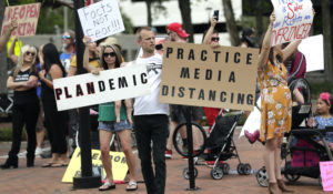 Protesters demanding Florida businesses and government reopen, march in downtown Orlando, Fla., Friday, April 17, 2020. Small-government groups, supporters of President Donald Trump, anti-vaccine advocates, gun rights backers and supporters of right-wing causes have united behind a deep suspicion of efforts to shut down daily life to slow the spread of the coronavirus. (AP Photo/John Raoux)