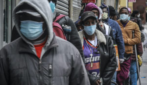 People wait for a distribution of masks and food in the Harlem neighborhood of New York on April 18, 2020. Black Americans have faced a combination of stressors hitting simultaneously: isolation during the pandemic, a shortage of mental health care providers and racial trauma inflicted by repeated police killings of Black people. Black people suffer disproportionately from COVID-19 and have seen soaring rates in youth suicide attempts. (AP Photo/Bebeto Matthews, File)