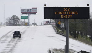 A truck drives past a highway sign Monday, Feb. 15, 2021, in Houston. A frigid blast of winter weather across the U.S. plunged Texas into an unusually icy emergency Monday that knocked out power to more than 2 million people and shut down grocery stores and dangerously snowy roads. (AP Photo/David J. Phillip)