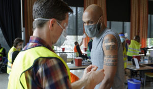 Shawn Brown, right, receives the second does of the Moderna COVID-19 vaccine from a volunteer worker at left, at a mass vaccination clinic at Seattle University, Friday, Feb. 26, 2021, in Seattle. (AP Photo/Ted S. Warren)