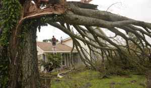 A man moves off the roof of his home as he and his parents repair the roof after Hurricane Ida moved through Monday, Aug. 30, 2021, in LaPlace, La. (AP Photo/Steve Helber)