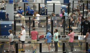 Travelers wear face coverings in the queue for the north security checkpoint in the main terminal of Denver International Airport Tuesday, Aug. 24, 2021, in Denver. (AP Photo/David Zalubowski)