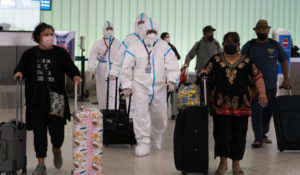 Air China flight crew members in hazmat suits walk through the arrivals area at the Los Angeles International Airport in Los Angeles, Tuesday, Nov. 30, 2021.  A vaccinated Californian who recently traveled from South Africa has tested positive for the variant. (AP Photo/Jae C. Hong)