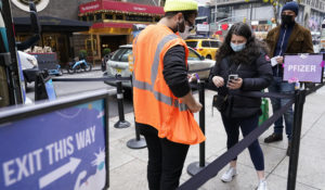 A health care worker, left, checks people in at a NYC mobile vaccine clinic in Midtown Manhattan, Monday, Dec. 6, 2021. (AP Photo/Mary Altaffer)